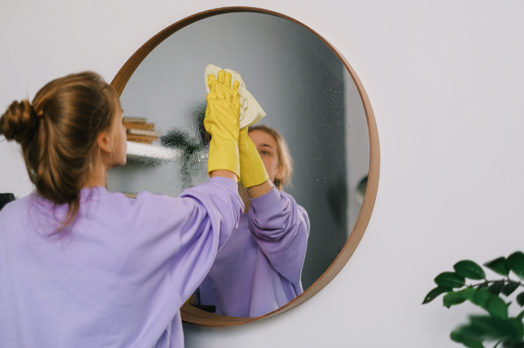person cleaning a mirror